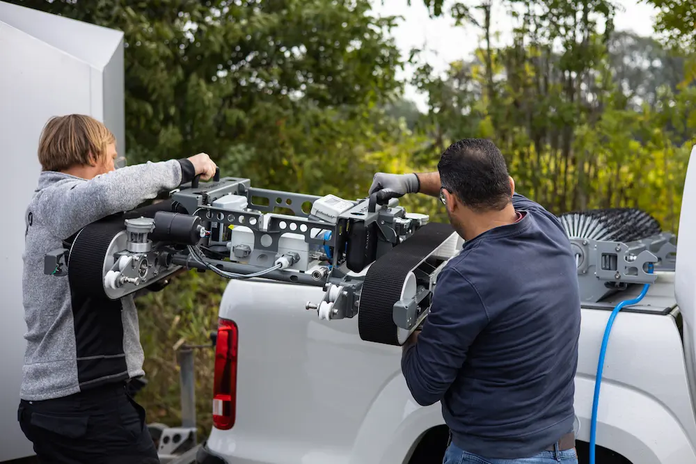 Robosun_Gallery_1 - Robosun Two technicians attach a large belt-driven mechanical rig to the back of a white pickup truck outdoors.