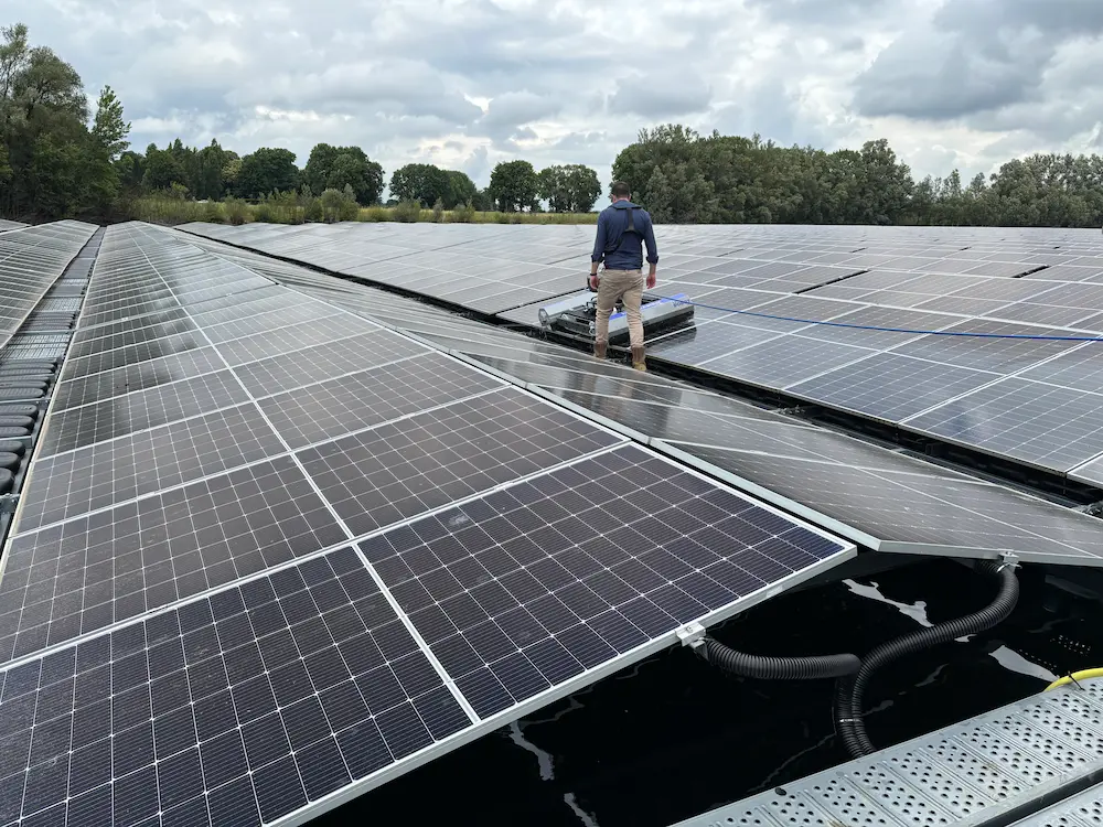 Robosun_Gallery_12 - Robosun Maintenance worker on a rooftop examining a large solar panel array under a cloudy sky.
