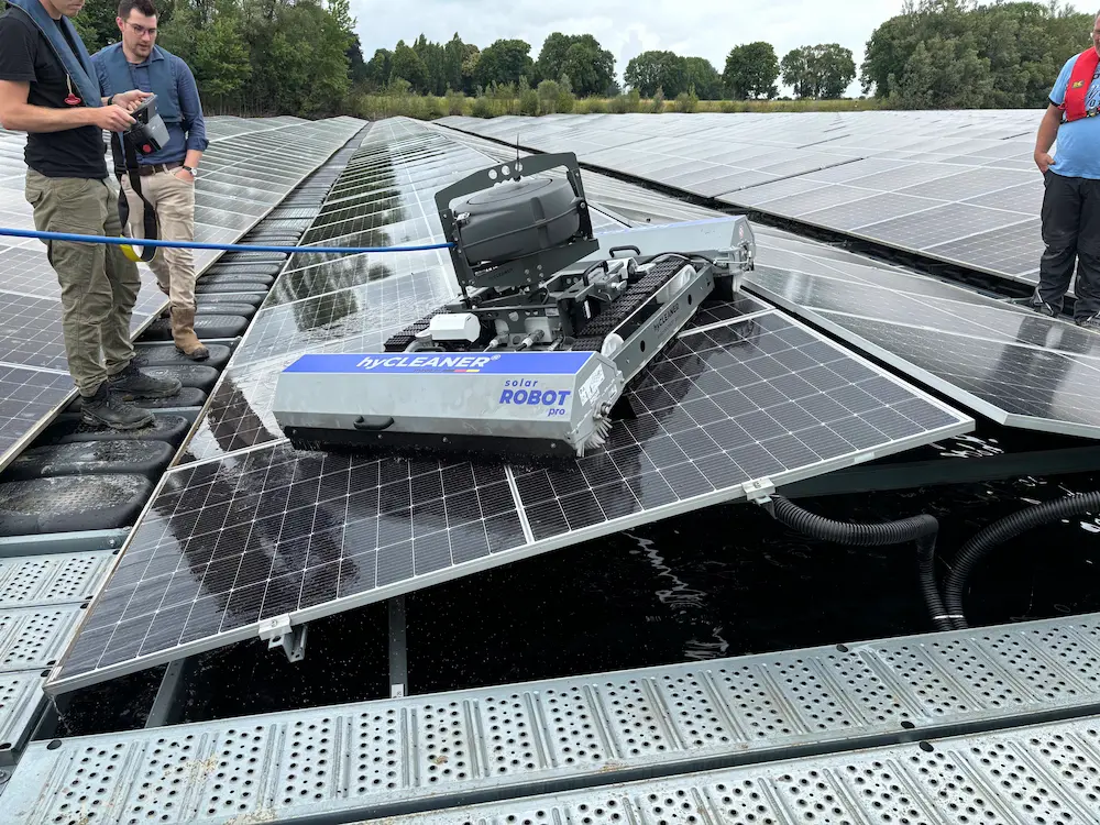 Robosun_Gallery_4 - Robosun Robotic cleaner operating on solar panels with workers standing nearby on a rooftop farm ground.