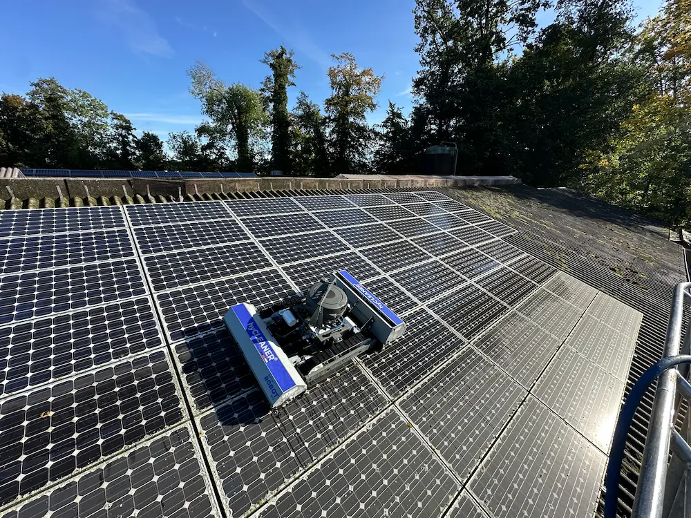 Robosun_Gallery_6 - Robosun Rooftop solar panels with a blue robotic cleaner moving across them on a sunny day.