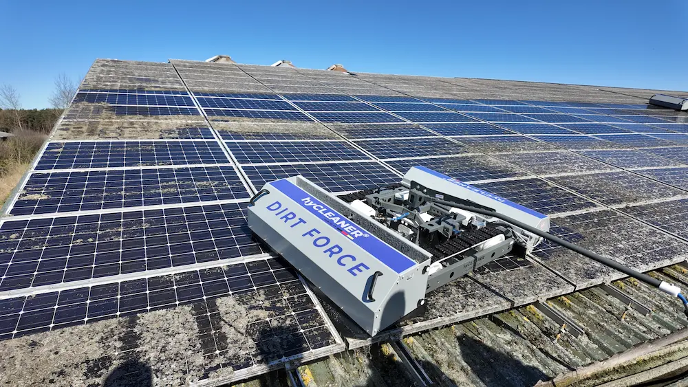 Robosun_Gallery_8 - Robosun Automated solar panel cleaner labeled 'DIRT FORCE' moving across dusty roof-mounted panels under a clear blue sky.